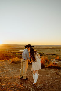 engagement photo of couple kissing as the sun sets