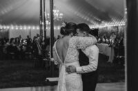A newlywed couple standing close and dancing at their reception 