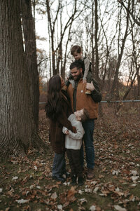 Paige Rini and her family gathered around a campfire in the woods during an outdoor session