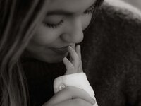 Close-up of a mother kissing her newborn’s tiny fingers, captured in black and white to preserve the emotional stillness of the moment.