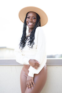 Smiling business owner wearing a hat and white shirt.