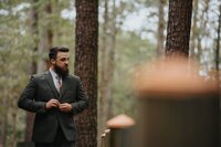 Groom walking buttoning jacket looking to the right.