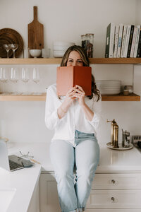 Freelance website copywriter Erika Fitzgerald sitting on a kitchen counter holding a notebook, planning copy for client websites