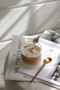 A transparent glass with an iced latte, on newspapers