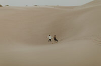 playful couple running in the sand dunes