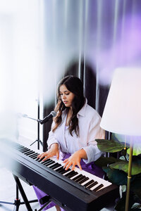 Musicians performing in front of vibrant purple and pink lights with synth equipment – bold music branding session by Mewphotovideo