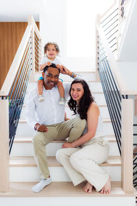 Parents sitting on stairs with a child on one of their shoulders
