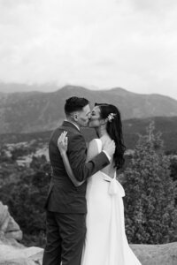 photo of bride and groom kissing while standing outside with mountains in the background taken by Colorado elopement photographer
