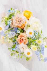 Beautiful close up shot of the brides flower bouquet on her wedding day featuring pops of blue, orange and white at the Highlands Ranch Mansion in Colorado.