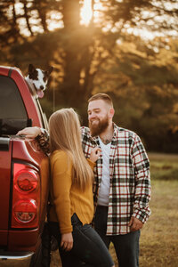 A couple leaning against a vintage truck, adding a touch of rustic charm to their love story, set in Vermont's picturesque landscape.