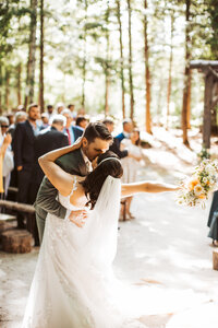 A bride and groom take a dip at the end of the isle after getting married.