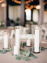 Glass cylinders with candles and greenery