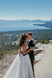 Bride in a deep red gown and groom popping champagne in a snowy forest near Lake Tahoe, celebrating their winter elopement with joy and laughter.