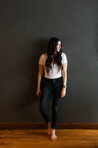 Allie Clark of Allie Clark Designs standing confidently in a minimal studio space, capturing her approachable, modern brand presence.