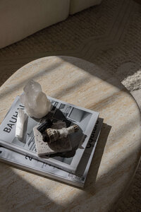 Spiritual tools including crystals, sage, and a smudging stick on a table bathed in sunlight