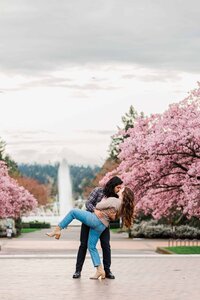 couple dip kissing in front of UW fountain and cherry blossoms