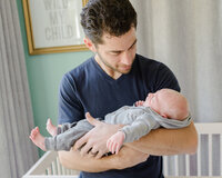 Father holding baby in nursery