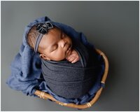 Blue Wrapped baby with hand peaking out in a basket