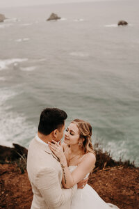 A Bride & Groom going in for a kiss on a the edge of a cliff