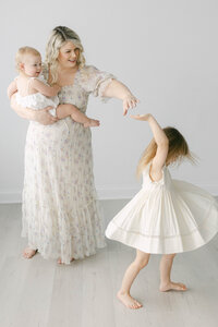 women with baby on her hip holding twirling daughters hand knoxville tennessee newborn photographer