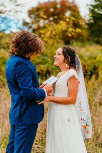 Groom reading vows to smiling bride during outdoor fall elopement in Virginia