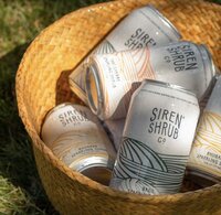 Social media post of a brown basket full of Siren Shrub cans