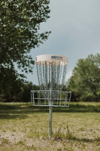 White disc golf basket outside in Davis County on disc golf course.