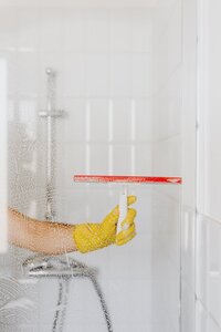 Hand using a squeegee to clean a shower door
