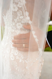 close up of a groom with his hand on his bride's waist