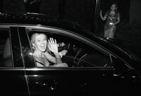 bride waves to camera in send off car