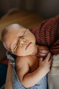 newborn baby sleeping in moms arms