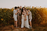 A family of seven snuggling together in front of a sunflower field in Bowie, Texas