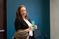 smiling woman holding a green piece of paper