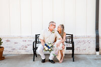Best friends get married at Steel Magnolia Barn wearing light golden colors and sitting on a bench laughing together