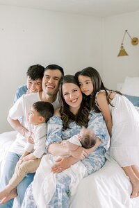 Dan and Katelyn Ng sit on their bed, surrounded by their four children.