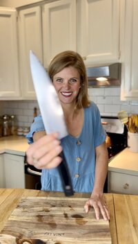 a woman in a blue dress smiling and holding a knife