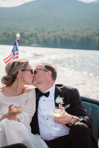 Newlyweds kiss with drinks in hand while on a boat