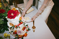 Bride cuts colorfully decorated wedding cake while celebrating at their reception at The Cordell in Nashville. 