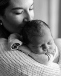 Mother snuggling newborn baby in black and white photo