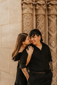 A person hugging their partner from behind as they both smile 