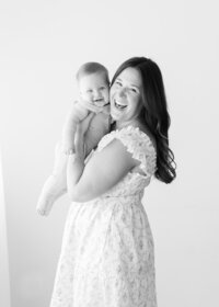Black and white photo of a mother and her baby with big smiles and snuggling cheek to cheek. Photo by Maegan R Photography
