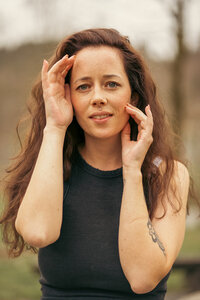 Ein gefühlvolles Porträt zeigt ein weibliches Model mit den Händen am Gesicht, das mit ausdrucksstarker Mimik Emotionen vermittelt.