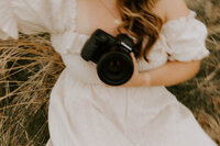 woman sitting in a field holding a camera