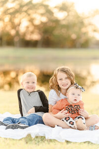 children sit on a picnic blanket by the pond in princeton texas by Tonaya Noel Photography