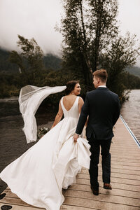 Bride and groom walking on a dock during their moody wedding day