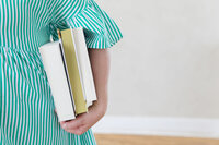 A woman holding three books under her arm to purchase