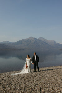 Elopement couple at lake mcdonald in glacier park. Bride is holding a floral bouquet