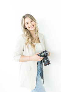 a woman smiling and holding a camera