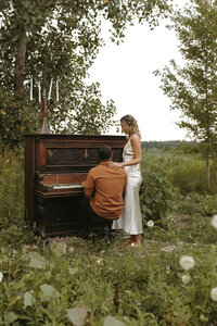 Couple playing piano together in an open field during their Michigan session