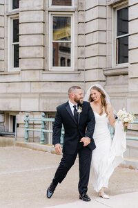 Bride and groom walking joyfully outside Pittsburgh courthouse, modern and romantic wedding captured by Pittsburgh wedding photographer Marien J. Malloy.